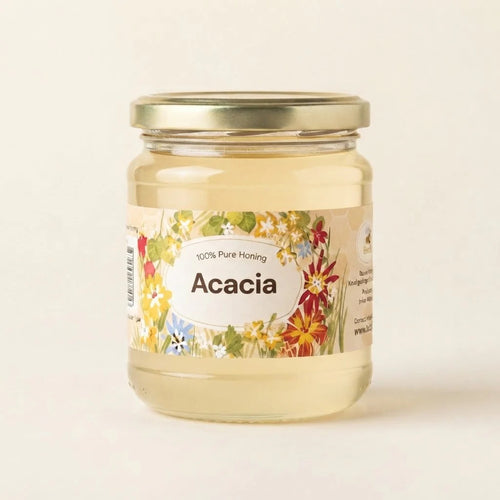A glass jar of Acacia honey with a gold metal lid and a colorful floral label, set against a plain off-white background.